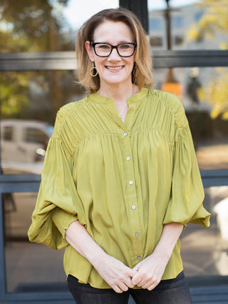 a lightweight button down top in green with billowing long sleeves great for modest seasonal wear