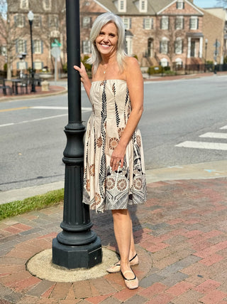 a charming beige strapless midi dress with a black and brown floral print worn with beige flats