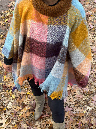 an oversized winter poncho in a plaid brown pattern with a warm high neck