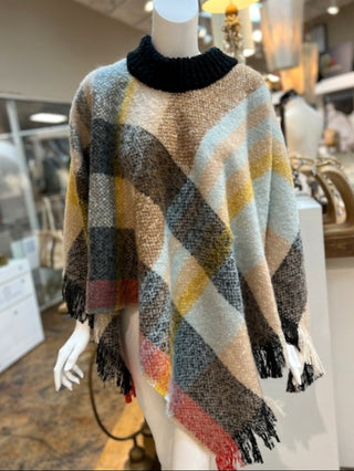 an oversized winter poncho in a plaid black pattern with a warm high neck