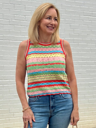 Woman wearing a colorful striped sleeveless top against a light gray wall.