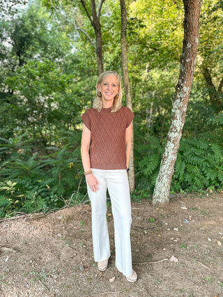 a brown cable knit sweater vest with short sleeves made to wear alone or layer in the fall and winter shown with white pants