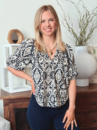 a billowy navy paisley print split neck top with short puff sleeves