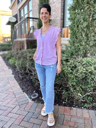 soft lilac pink v neck sleeveless top with ruffle detail and button down design worn with blue jeans