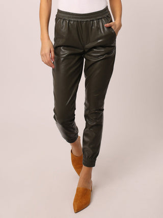 a pair of comfortable vegan leather green joggers with a stretch waist shown with suede shoes