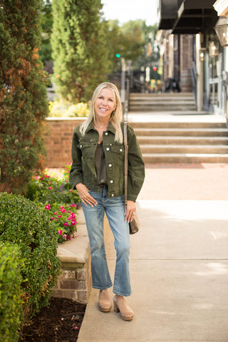an olive green shacket with silver buttons and a relaxed silhouette perfect for fall fashion layering shown with denim pants