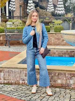 a trendy cropped blue denim quilted jacket worn with blue jeans and a black top