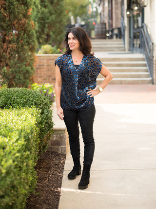 a sheer navy velvet blouse with orange leopard print and short sleeves perfect for seasonless luxury shown with black pants