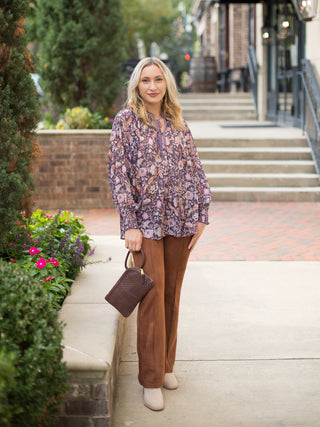 a purple bohemian blouse with flower print and flowing sleeves perfect for relaxed chic fashion shown with suede pants