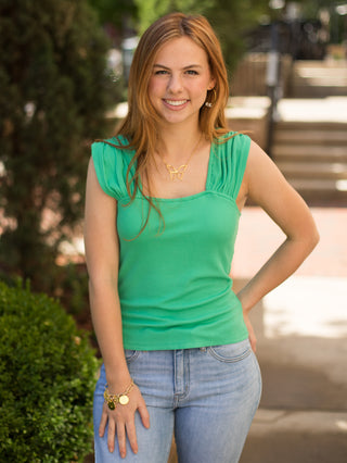 a stretch knit shamrock green top with a square neckline and ruched shoulder detail along the cap sleeves