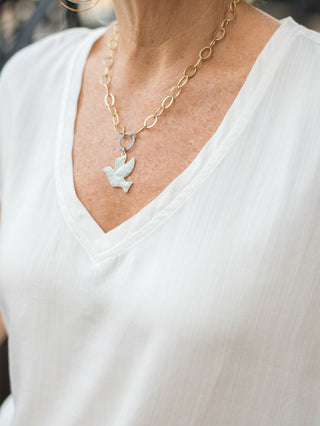 a lightweight white t shirt with a v neckline and sleeveless silhouette shown with a dove necklace