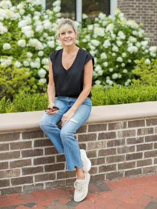 a lightweight black t shirt with a v neckline and sleeveless silhouette shown with denim pants