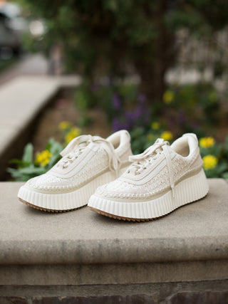 a pair of off white sneakers with knit texture and a ribbed platform sole