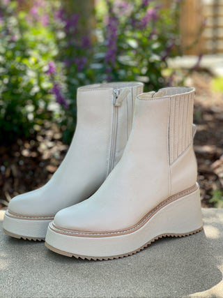 a pair of off white leather waterproof boots with platform heels and a side zipper great for unpredictable weather
