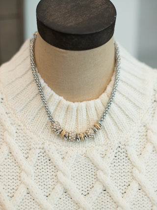 a silver chain statement necklace with chunky silver and gold pendants that hit above the collar bone