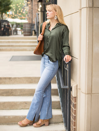 a forest green silk button down blouse with long sleeves perfect for day to night dressing in any season shown with denim