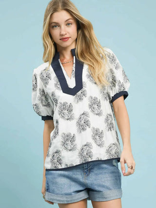 a bold abstract white blouse with a blue embroidered floral pattern