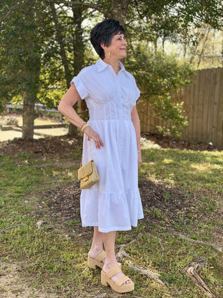 a white collared midi dress with buttons down the front and a cinched waist worn with beige heels