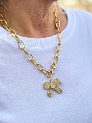 a large gold oval link necklace with an etched butterfly pendant