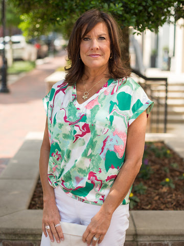 a v neck short sleeve blouse in shades of kelly green with pops of pink and blue with a loose fit