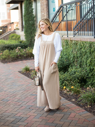 a light beige relaxed fit jumpsuit with a wide leg silhouette and pockets made for cozy fall fashion shown with a white top
