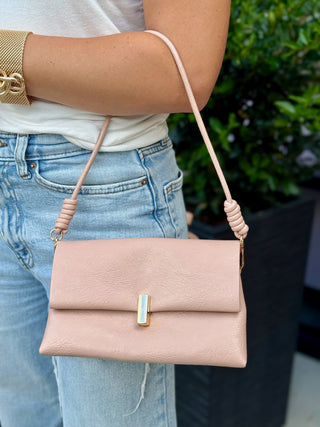 a sleek pink faux leather crossbody bag with a gold twist lock