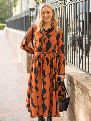 a retro printed midi dress in orange and black with long sleeves with a tie waist perfect for modest dressing
