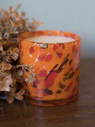 a pumpkin spice candle in an orange speckled glass vessel perfect for fall and halloween decor