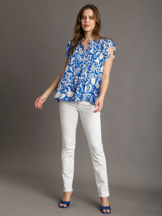 vibrant tropical blue floral print top with short ruffle sleeves and flowy box cut design worn with white pants