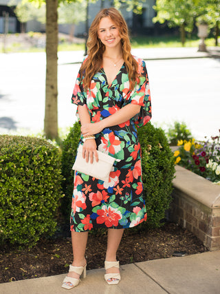 this black multi-colored floral mini dress has a plunge v-neck and kimono sleeves paired with white sandals