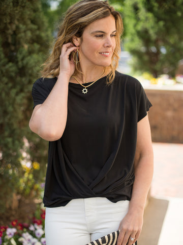 sleek black top framed by short sleeves with a front twist detail has curved neck and high low hem
