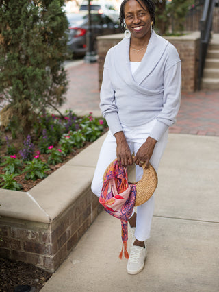 a light gray wrap top with a v neckline and long sleeves shown with white pants