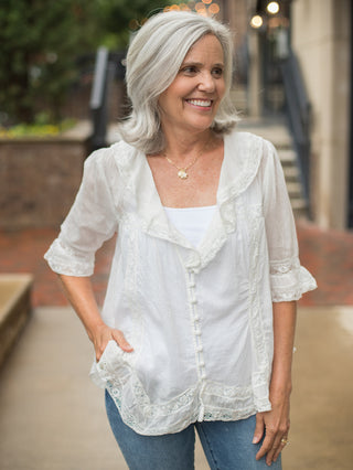a relaxed fit ivory button down blouse with lace ruffle detailing and three quarter sleeves