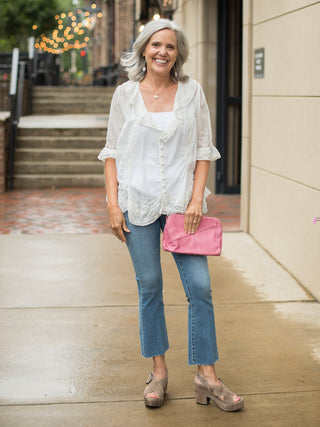 a relaxed fit ivory button down blouse with lace ruffle detailing and three quarter sleeves shown with denim pants