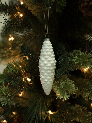 a classic white christmas tree ornament in the shape of a pinecone coated in silver glitter perfect as a holiday hostess gift