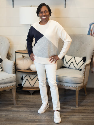 a colorblock sweater in navy white and gray in a flattering fit perfect for fall and winter fashion shown with white pants