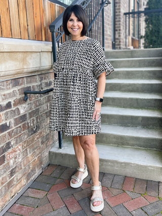 geometric print mini tunic babydoll style dress in black and ivory with short bell sleeves worn with beige platform sandals
