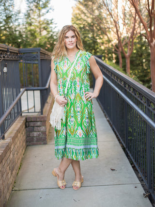 flowy bright green global inspired sleeveless midi dress worn with sand colored sandals