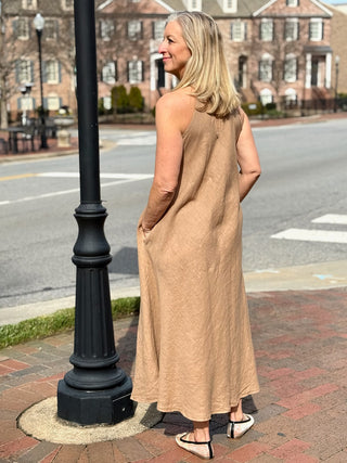 a long and flowy natural colored mock neck maxi dress worn with neutral flats