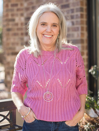 a pink crochet sweater with a round neckline