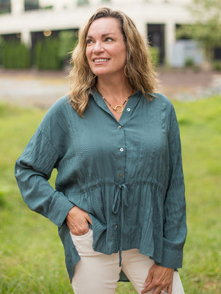 a long sleeve button down blouse in teal with a tie at the waist and relaxed fit perfect for cozy fall fashion