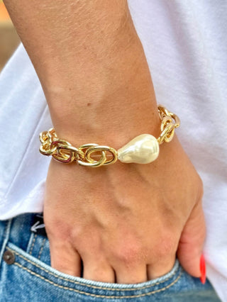 a chunky gold link bracelet with a large pearl accent piece