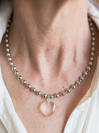 a silver beaded necklace with a glass heart charm