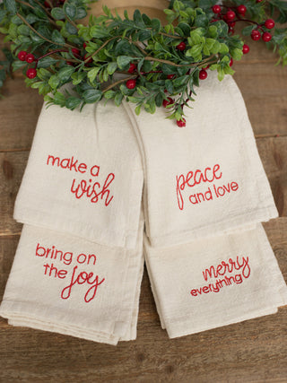 a collection of beige napkins with red embroidered sentiments for christmas holiday home decor and host gifts