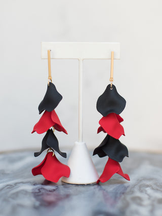a pair of red and black statement earrings made of fabric petals perfect for fall fashion and uga game days