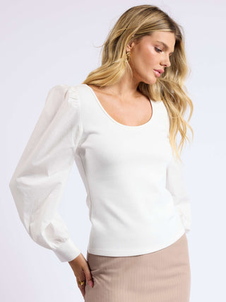 a tight white knit top with billowy long sleeves