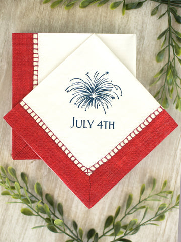 a pack of white cocktail napkins with red trim and blue fireworks that reads july 4th