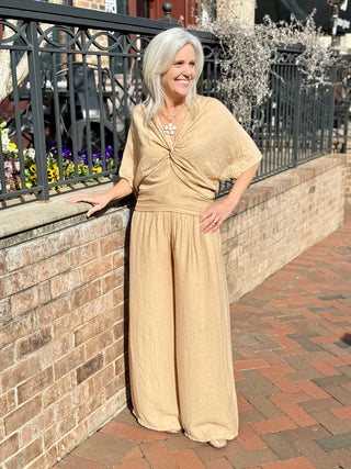 a chic neutral camel colored blouse with a deep v neck and twist detail worn with camel pants