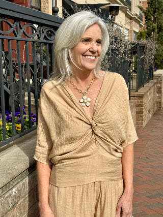 a chic neutral camel colored blouse with a deep v neck and twist detail