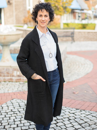 wear this black knee length cardigan with a structured collar and pockets as a classic everyday winter layer